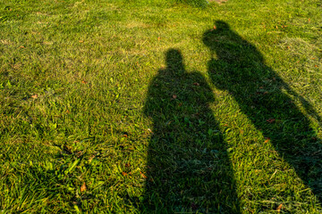 two shadows on the green grass. Shadows of people on green grass.