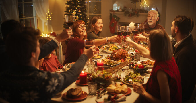 Parents, Children and Friends Spend Christmas Dinner Together at Home. Multicultural Family Raising Wine Glasses and Toasting, Celebrating a Holiday with a Delicious Turkey Meal