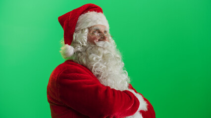 Studio Shot Isolated Mockup Template: Jolly Santa Claus Standing On Green Screen Chromakey Background With Hands Crossed, Looks At The Camera Cheerfully. Christmas, New Year, Celebration