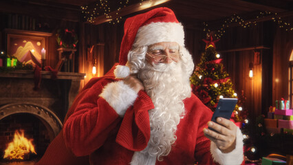 Happy Santa Claus with White Fluffy Beard and a Red Costume is Using a Smartphone. Accepting Online...