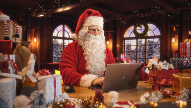 Arc Shot of Father Christmas Sitting and Using a Modern Laptop Computer. Santa is Browsing Online, Communicating with Clients, Managing a Successful Online Shopping Business with Gifts for Children