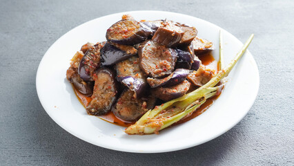(Terong Balado) Balado eggplant served on a white plate. Single object. Table tops.