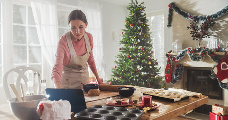 Portrait of a Woman Using Digital Tablet to Follow an Online Recipe While Cooking Dinner for Christmas Eve. Housewife Watching a Tutorial or Cooking Show to Prepare Food for her Guests on Holiday