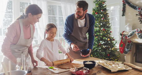 Happy Family During Christmas: Portrait of Little Cute Girl Learning How to Make Cookies and Celebrating her Achievement with her Parents. Cute Family Preparing Together for Holiday Dinner