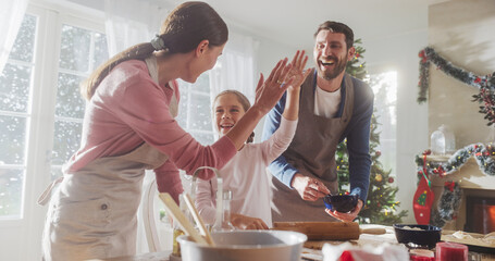 Happy Family During Christmas: Portrait of Little Cute Girl Learning How to Make Cookies and Celebrating her Achievement with her Parents. Cute Family Preparing Together for Holiday Dinner - obrazy, fototapety, plakaty