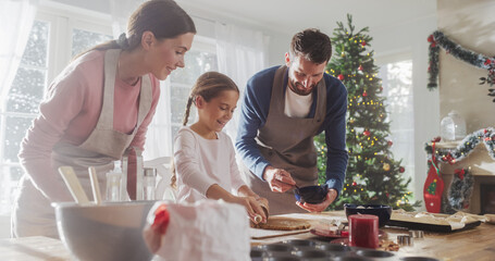 Family Celebrating the Holidays: Parents and Child Baking Together During Christmas. Cute Little Girl and Parents Making Gingerbread Cookies. Happy Childhood Memories