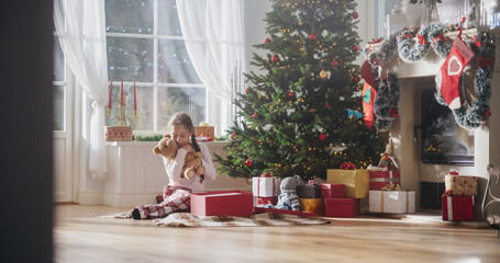 Happy Little Girl Waking Up on Holiday Morning to Receive New Toys from Under the Christmas Tree. Cute Child Getting Her Gift from Santa