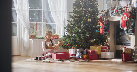 Happy Little Girl Waking Up on Holiday Morning to Receive New Toys from Under the Christmas Tree. Cute Child Getting Her Gift from Santa