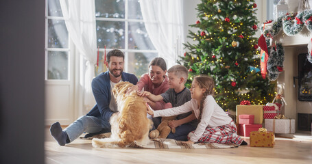 Portrait of Family at Home Sitting Next to a Christmas Tree, Petting Their Purebred Golden...