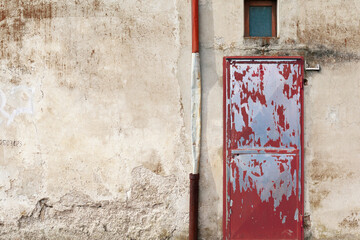 Red iron door on weather damaged wall