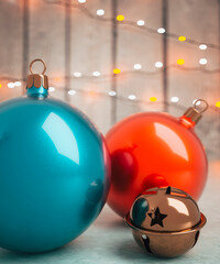 Shiny red and blue baubles with sleigh bells close up on a table with Christmas lights in the background 3d render