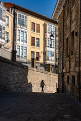 Fototapeta na wymiar Female tourist walking through the narrow streets of the old town of the medieval city of Vitoria, Basque Country.