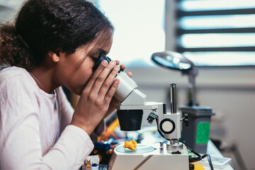 Smart Young African American Schoolgirl is Studying Electronics and Soldering Wires and Circuit Boards in Her Science Hobby Robotics Project. Girl is Working on a Robot in Her Room. Education Concept.