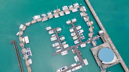 Aerial drone view of Chalong Pier in Phuket, Thailand. Many boats, yachts and speed boats moored at the pier platform of Ao Chalong Bay, one of centers to travel around Andaman Sea.