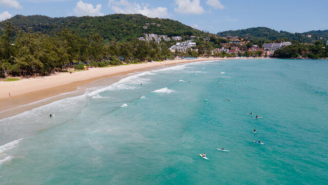 Aerial view of Kata Beach with surfers riding waves on surfboards during the low season. One of the popular travel destinations in Phuket, Thailand. Beautiful summer scenery of Andaman Sea
