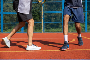 Two unrecognizable men playing basketball in court outdoors.