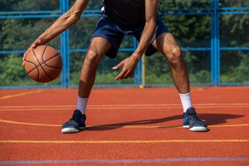 Unrecognizable man playing basketball at court.