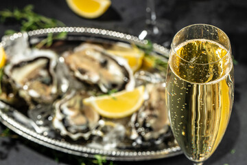 fresh oysters and lemons in bowl near champagne glasses. banner, menu, recipe place for text