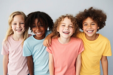 Happy smiling children of different culture and race wearing colorful t-shirts on a plain gray background. Concept of cheerful friends, happy childhood
