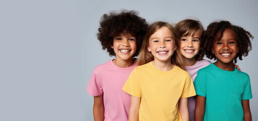 Happy smiling children of different culture and race wearing colorful t-shirts on a plain gray background. Concept of cheerful friends, happy childhood
