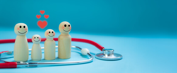 Health insurance concept, wooden dolls, family of parents and children, happy smiling faces, surrounded by stethoscopes, bright blue background.