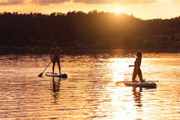 Sea woman and man surfing on SUP board.