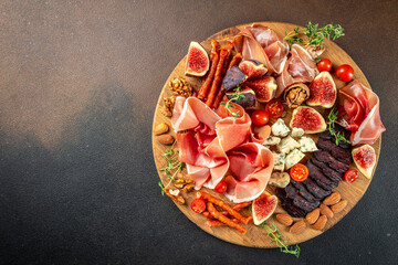 spanish tapas set, cheese and meat variety board on a dark background. top view. place for text