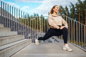 Fitness sport woman in sportswear doing sports on the street, outdoor sports. Athletic woman doing stretching exercises. Active lifestyle.