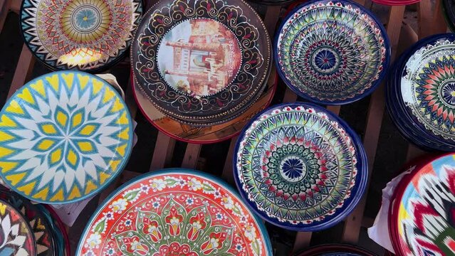 Uzbek national ceramic tableware in Tashkent - June 29, 2023: Goods at the Oriental Bazaar in Uzbekistan. Chorsu Market. Plates, teapots, cups. Painting with floral ornament. 4K