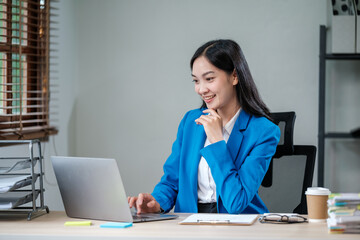 Professional business woman manager executive wearing suit looking at laptop computer technology in office working on digital project sitting at desk.