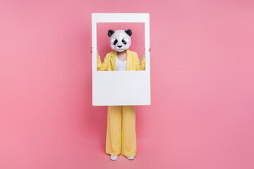 Full length photo of eccentric 3d panda mask person hands hold paper album set card isolated on pink color background © deagreez
