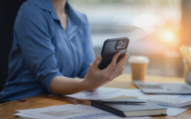 Asian businesswoman using smartphone sitting at desk in office, working online, 