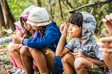Group of curious happy school kids in casual clothes exploring nature and forest together - The...