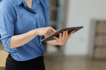 Asian woman working with tablet and standing at in workplace office.