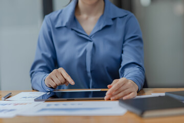 Asian woman working with document papers and tablet sitting at desk workplace office.