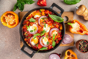 Shakshuka. Fried eggs with vegetables in a cast iron pan, traditional middle eastern traditional dish place for text, top view