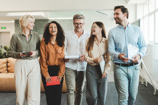 Group of positive handsome businesspeople, students, managers walking, working in modern office