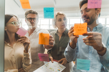 Group of serious confident businesspeople using sticky notes, agile methodology for productivity