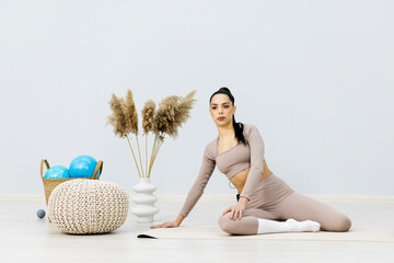 A beautiful young woman with a slim figure does sports exercises isolated on a light background. Self-love. The concept of beauty, style, fashion, cosmetology, body and skin care, sports, advertising.