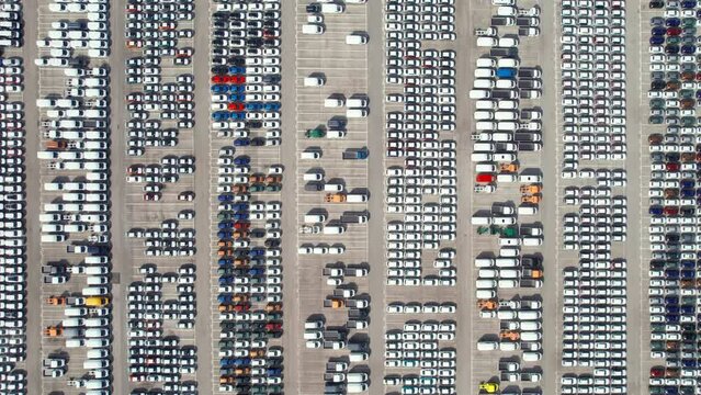 Aerial top down view of new cars parked for sale in a stock lot row