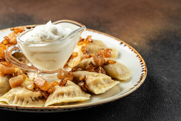 vareniki with potato filling and fried onions, Ukrainian cuisine on a dark background. place for text