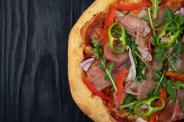 Hot tasty traditional Italian pizza with bacon and vegetables on a dark background