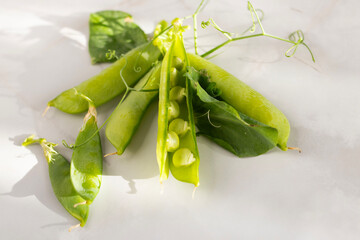 young green peas in pods on a light background