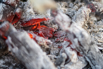 Dark black background of burnt wood with red hot embers still burning.