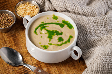 Creamy mushroom soup in a white plate on a wooden background