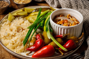 Pickled vegetables with sauerkraut and mushrooms on a wooden background. Selective focus.