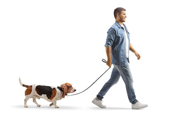 Full length shot of a young man walking a basset hound dog on a lead