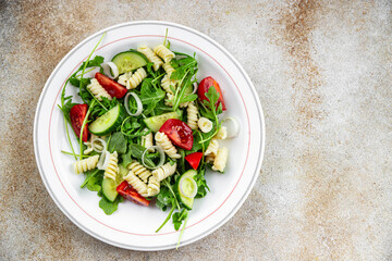 pasta salad fusilli pasta, cucumber, tomato, green lettuce, onion eating cooking meal food snack on the table copy space food background rustic top view
