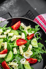 pasta salad fusilli pasta, cucumber, tomato, green lettuce, onion eating cooking meal food snack on the table copy space food background rustic top view