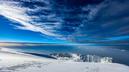 Clouds and blue sky above the snow covered summint of Mount Kilimanjaro © John